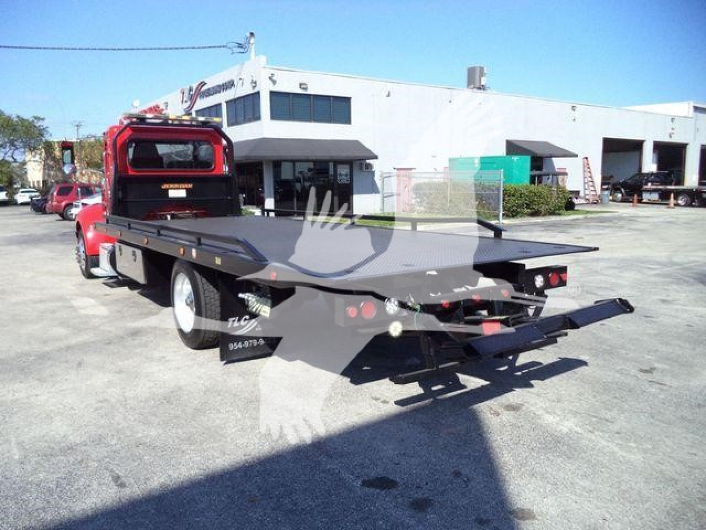 Flatbed rollback tow truck rear view showing flatbed and tail lights.