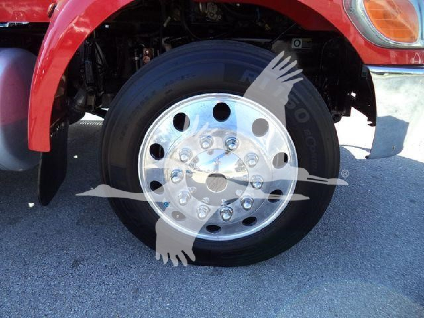 Peterbilt 337 front wheel assembly showing chrome steel wheel and tire with red fender and undercarriage components visible.