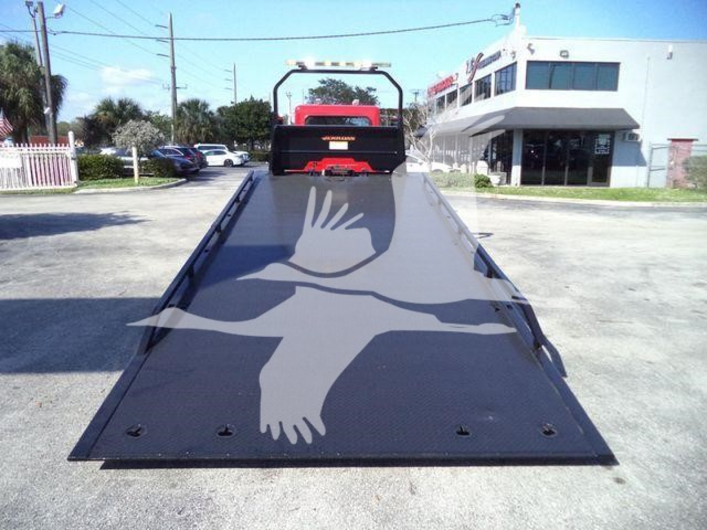 Peterbilt 337 rollback truck flatbed in driveway, rear view showing long black steel ramp with hinge points