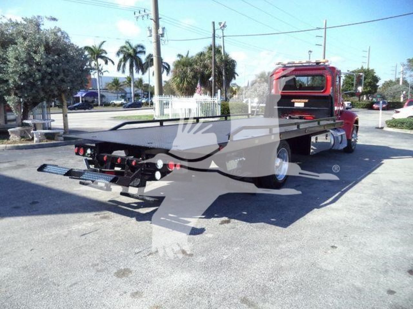 Peterbilt 337 rollback flatbed truck viewed from rear quarter, red cab, flatbed with hitch and rear lights visible