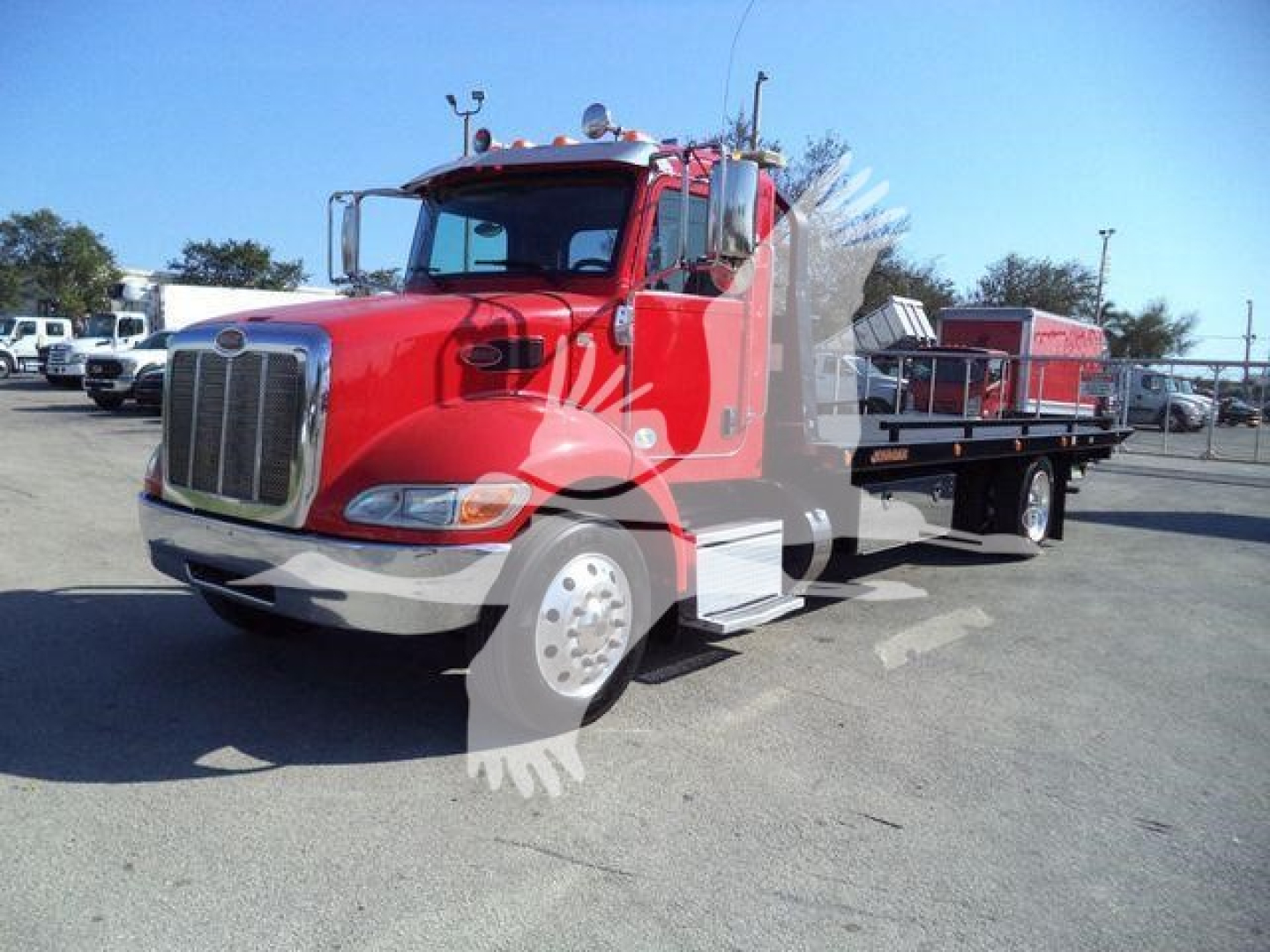 Peterbilt 337 rollback truck in red, front-left view showing cab and flatbed with equipment on the back.