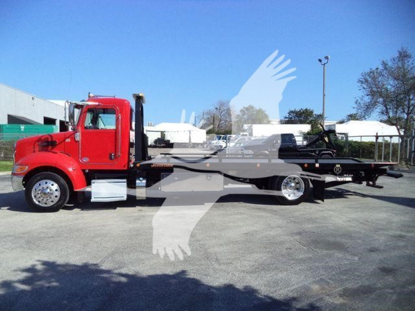 Peterbilt 337 rollback truck in red cab with flatbed, side view showing extended trailer and equipment