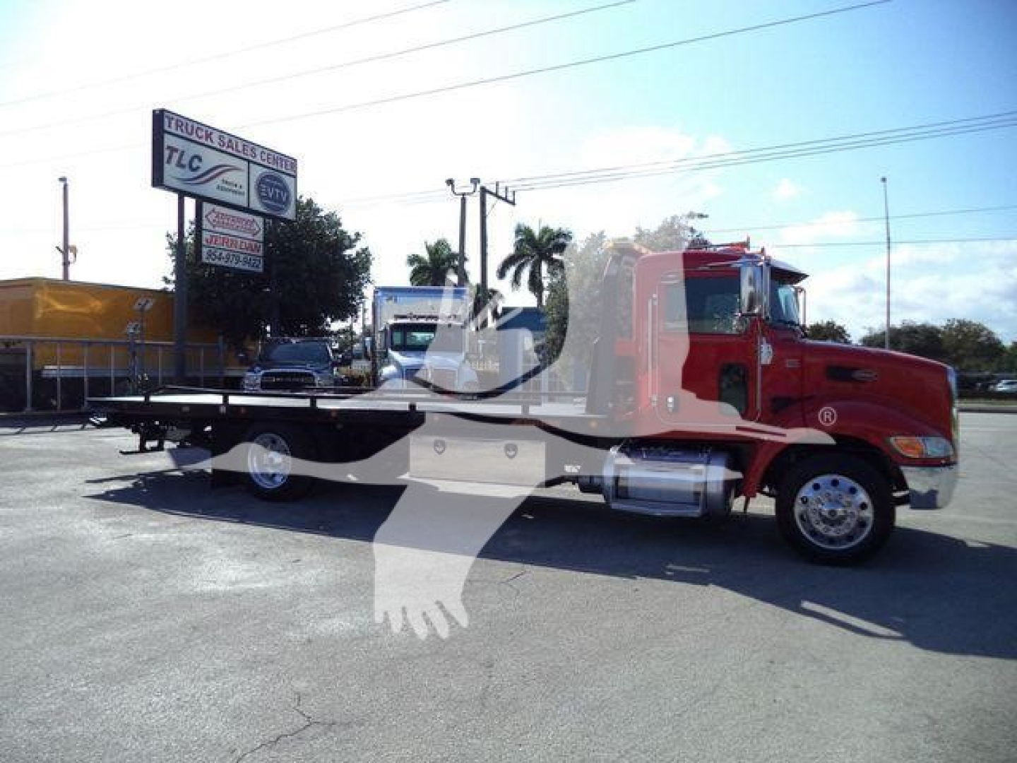 2020 Peterbilt 337 rollback tow truck side view showing flatbed, red cab, chrome fuel tanks, and wipers with dealership in background.