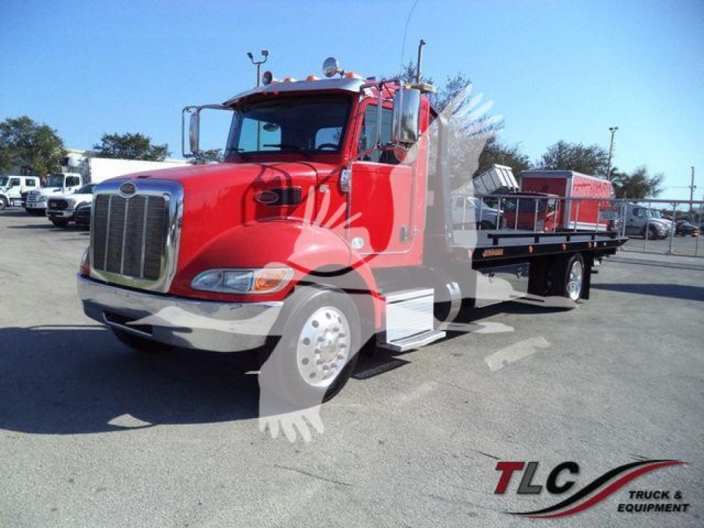 Peterbilt 337 rollback truck in red with flatbed and chrome grille, side view showing tow equipment and extended cab.