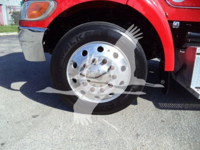 Truck wheel and front fender of a 2020 Peterbilt 337 rollback truck showing front wheel and bumper.