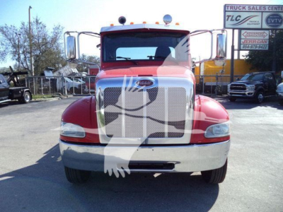 Truck front view showing Peterbilt grille, bumper, and headlights in a truck yard.
