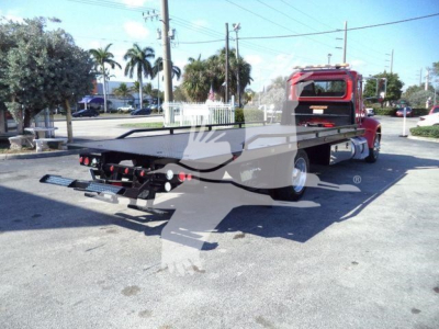 Peterbilt 337 rollback flatbed truck viewed from rear quarter, red cab, flatbed with hitch and rear lights visible