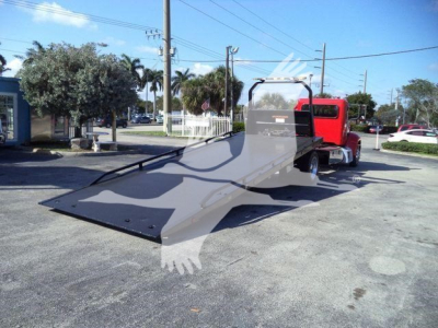 Peterbilt 337 rollback tow truck in-service view with a lowered flatbed and red cab.