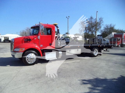 Peterbilt 337 rollback truck red cab with flatbed, side view showing front grille and wheel, stock number and dealership watermark overlay.