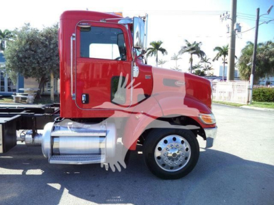 Red Peterbilt 337 rollback truck side view showing cab, chrome fuel tanks, and front wheel with polished rim.