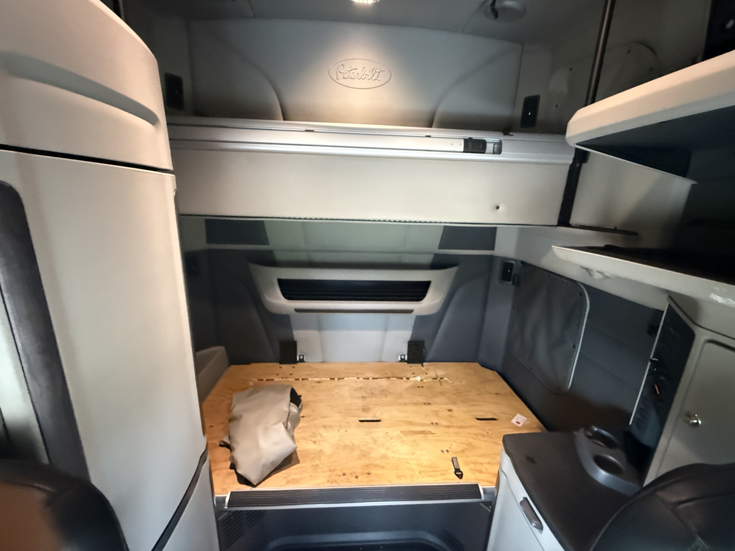 Peterbilt 579 truck cab interior sleeper area with wood deck floor and storage compartments.