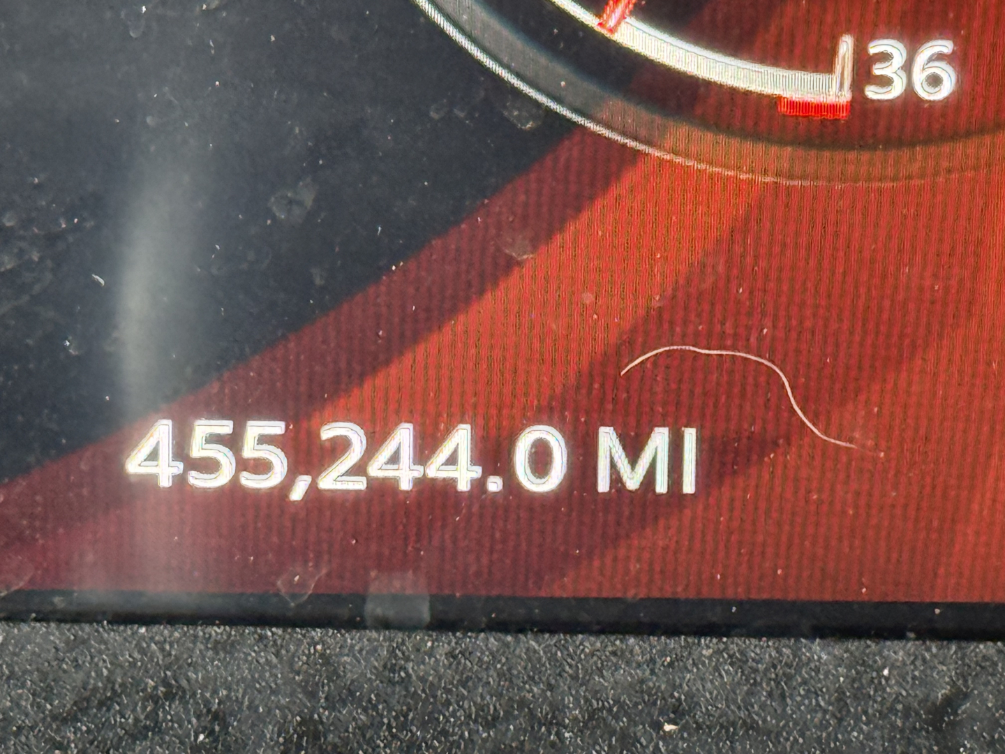 Instrument cluster displaying mileage 455,244.0 MI in a Peterbilt truck, part of the gauge with numbers and red dial visible.