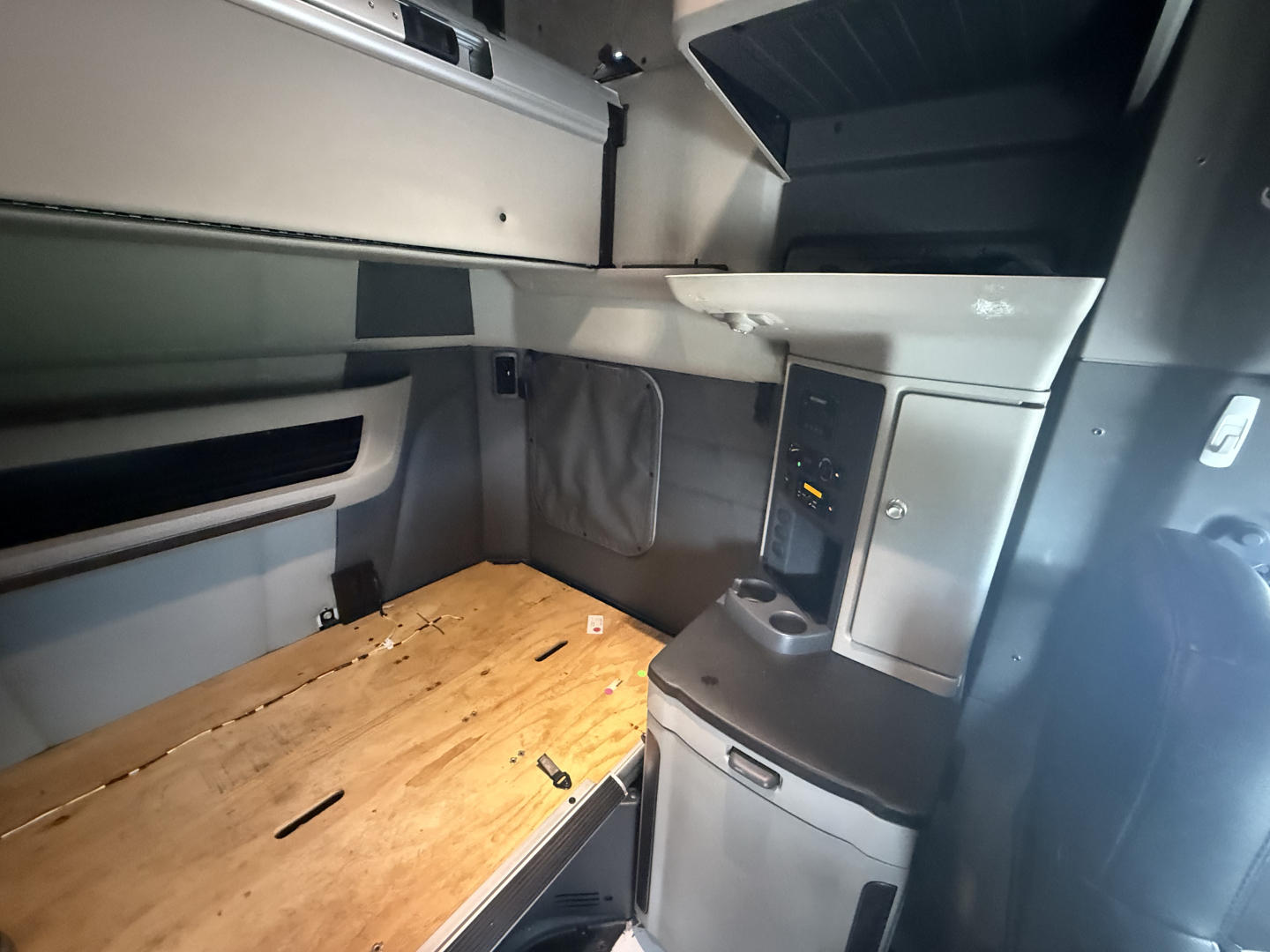 Peterbilt 579 sleeper cab interior showing upper storage compartments and wooden bed platform in the back of the cab.