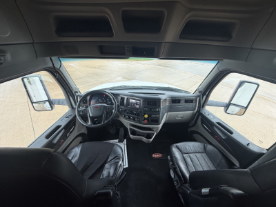 Peterbilt 579 cockpit interior view showing steering wheel dashboard center console and driver/passenger seats.