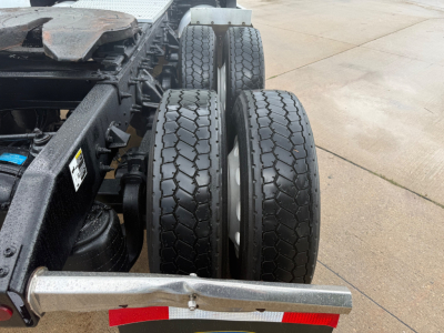 Trucks chassis side showing dual rear axles with twin tires and metal bumper, Peterbilt 579 undercarriage components visible.