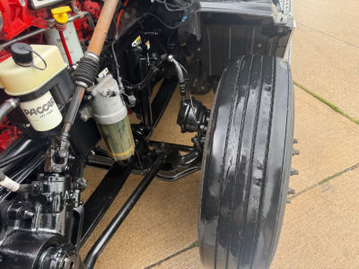 Peterbilt 579 front wheel area with exposed suspension and hydraulic components; visible fluid reservoirs and hoses.
