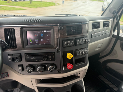 Peterbilt 579 truck interior dashboard view with infotainment screen, control knobs, and gear selector area visible.