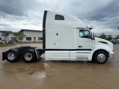 Peterbilt 579 tractor in profile view showing sleeper cab, white exterior, dual rear axles, and chassis area.