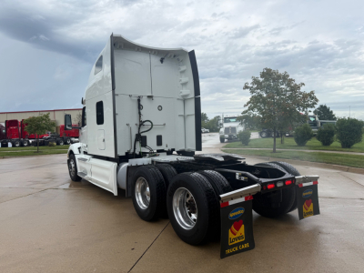 Peterbilt 579 tractor in a truck lot, rear view of cab and dual rear axles, white exterior with sleeper, no visible branding details.
