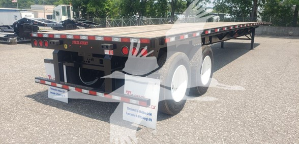 Dorsey air sliding tandem flatbed trailer showing rear and tandem axle configuration with white wheels and reflective tape.