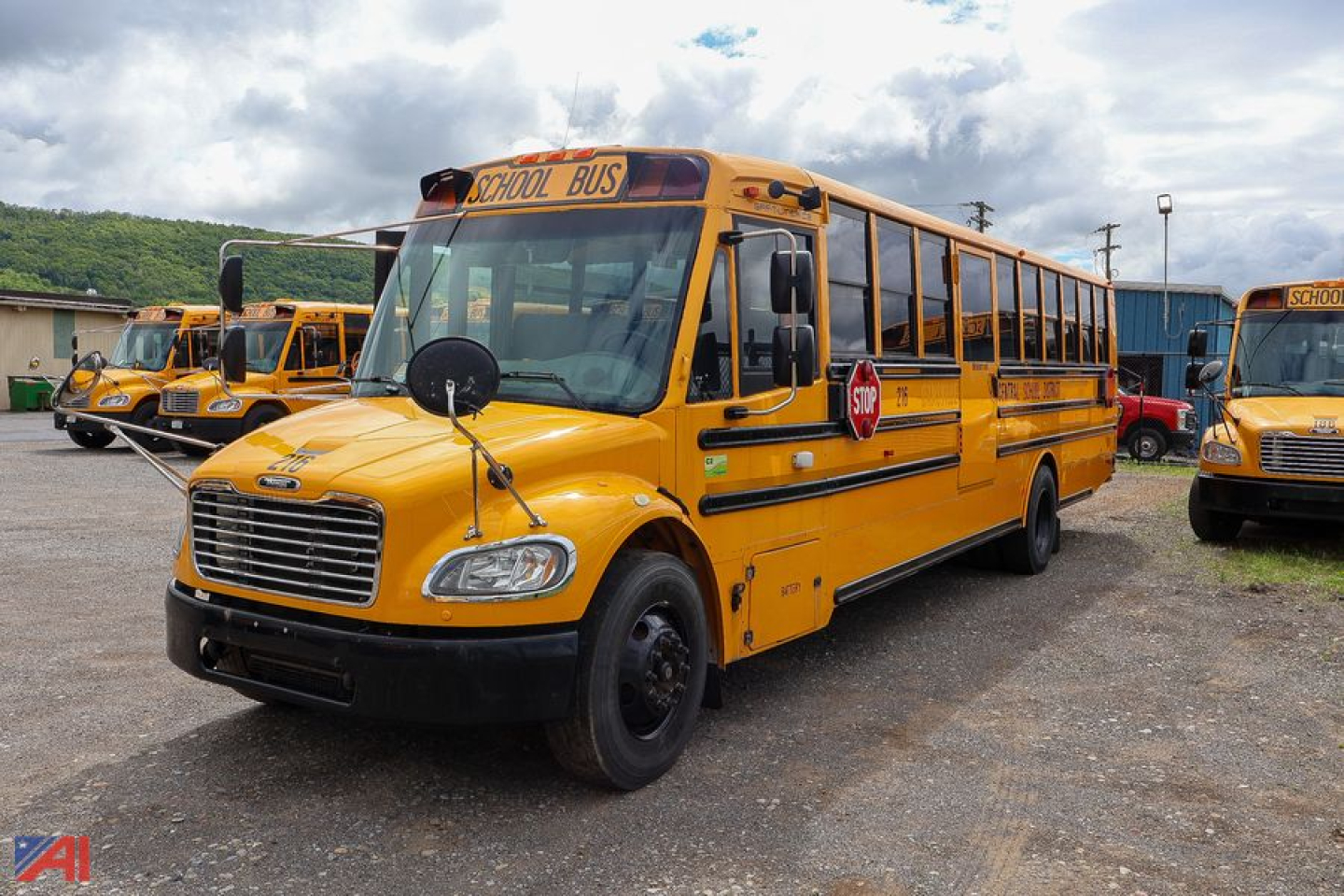 School bus front left view showing yellow Freightliner C2 Saf-T-Liner with stop sign and school bus text on the side and roof.