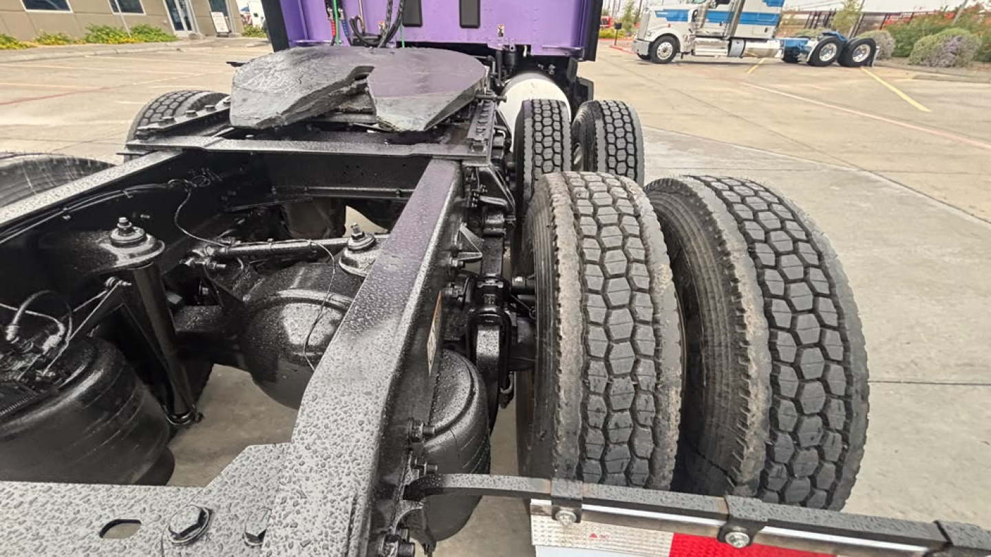 Vehicle chassis of a Kenworth truck showing rear axle assembly and fifth wheel area with dual rear axles and tires.