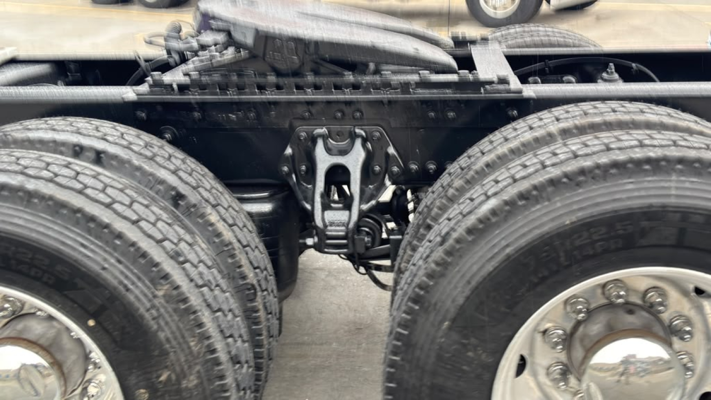 Chassis view of a Kenworth T680 tractor showing rear frame, suspension hanger, round dual tires, and a center area with drivetrain components.