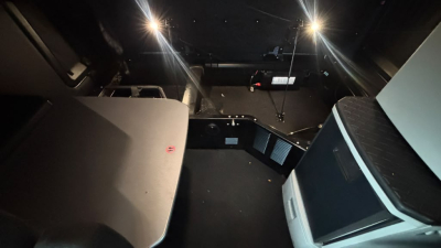 Cab interior of a 2024 Kenworth T680 truck showing dashboard area, seating, and ceiling with overhead shelf; no text visible.