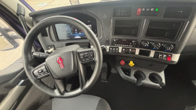 Interior of a Kenworth T680 cab showing steering wheel, dashboard, and center console with gauges and controls.