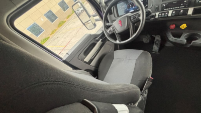 Kenworth T680 cab interior showing steering wheel, driver's seat, and dashboard with controls.