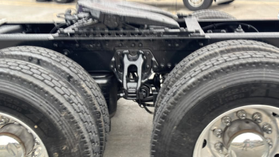 Chassis view of a Kenworth T680 tractor showing rear frame, suspension hanger, round dual tires, and a center area with drivetrain components.