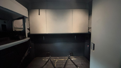 Kenworth T680 cargo area seen from rear with storage compartments and interior panels; trunk/box area empty showing side shelves and tie-down anchors.