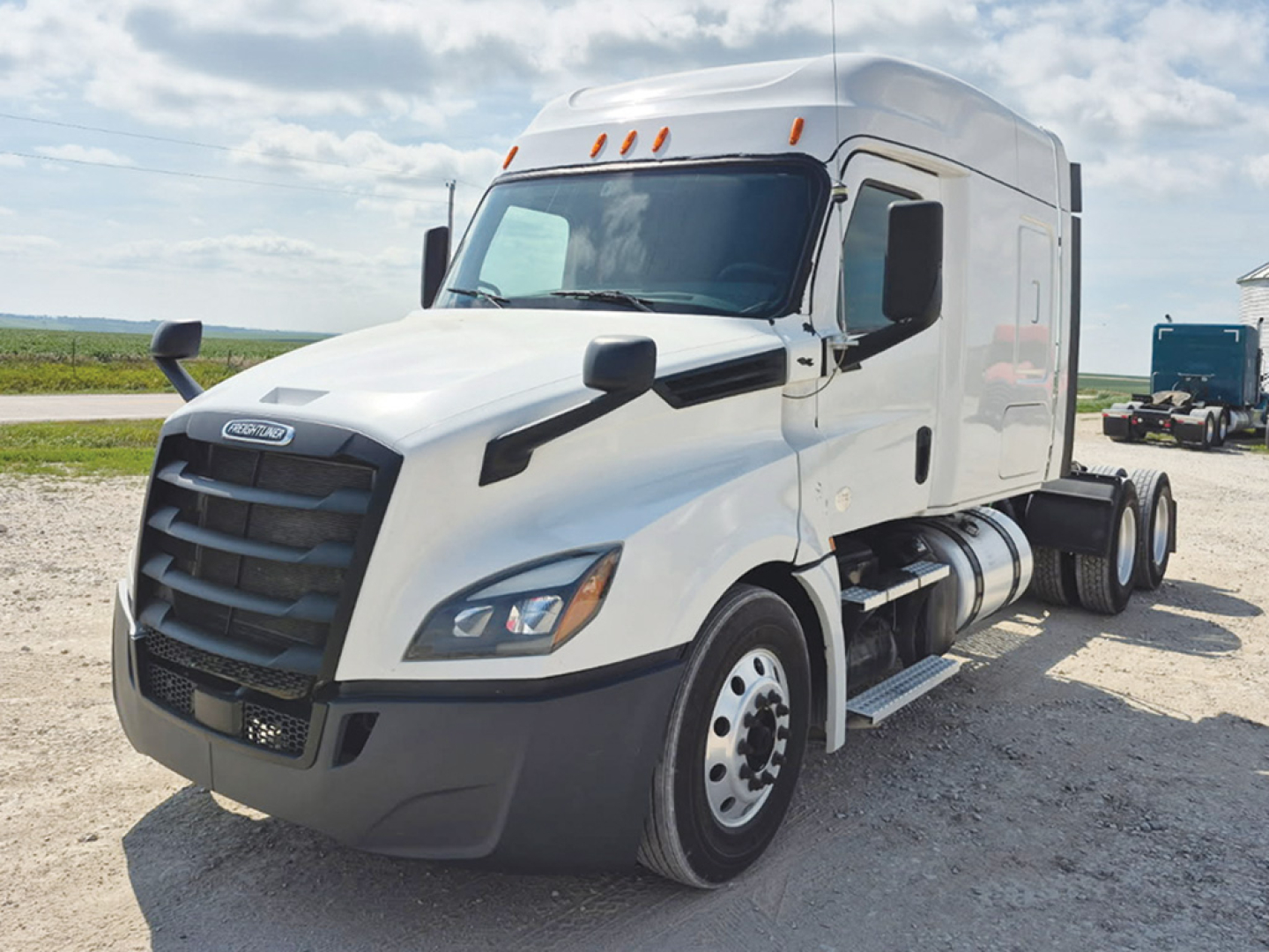 2020 Freightliner Cascadia126 conventional sleeper truck in a parking lot showing front grille, headlights, side mirrors, and fuel tanks.