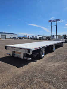 Manac Darkwing drop deck trailer in a dealership lot, three axles, aluminum deck, rear underride guard, taillights, and bumper.