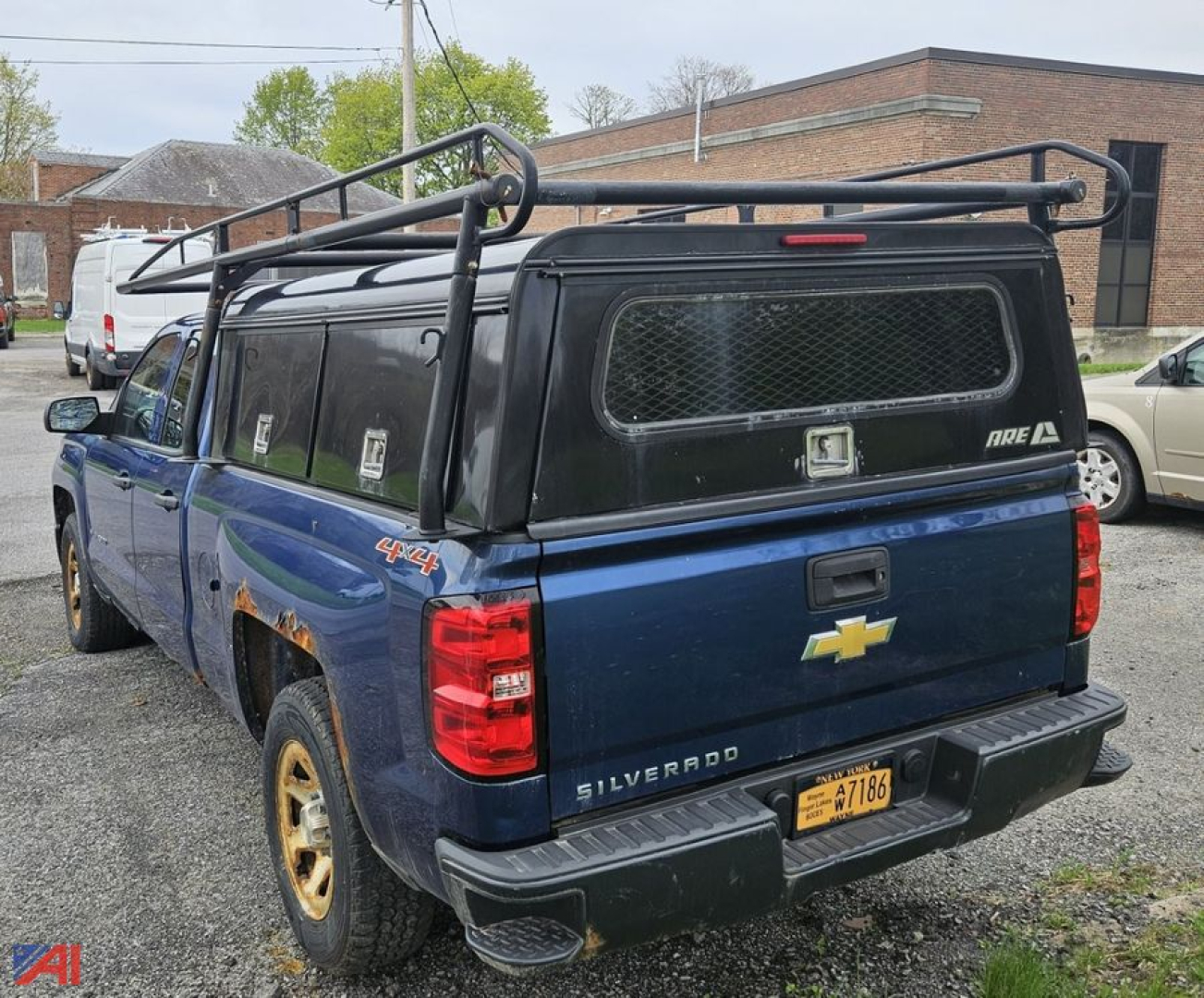 Chevrolet Silverado 1500 pickup with cap, 4x4, blue, rear view showing cap windows with metal grate and roof rack.
