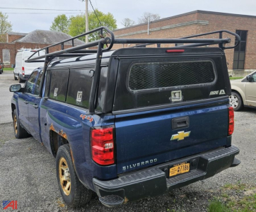 Chevrolet Silverado 1500 pickup with cap, 4x4, blue, rear view showing cap windows with metal grate and roof rack.