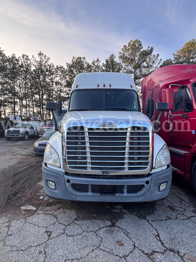 Freightliner Cascadia 125 front view showing chrome grille, large bumper, and raised roof sleeper in a used truck lot.