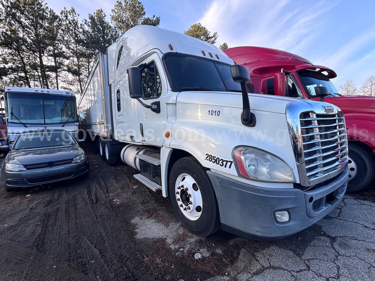 Truck front-left view showing Freightliner Cascadia 125 with large chrome grille, white cab, number 1010 and 2850377 on door and hood, side mirrors, and fog lights.