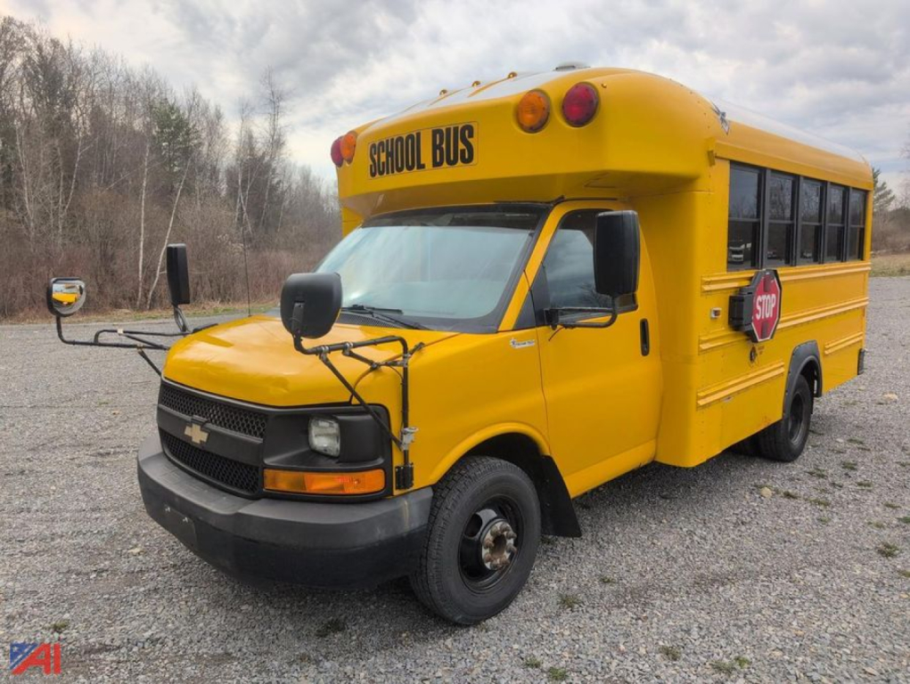 School bus in-service showing yellow Chevrolet Express school bus with STOP sign and 'SCHOOL BUS' label on hood and top, front view.