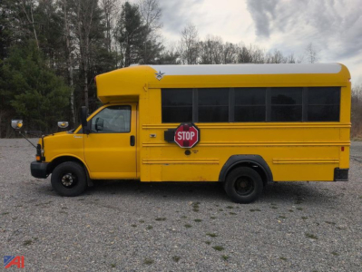 Yellow school bus in side view with stop sign, Chevrolet Express body style, black wheels, and oversized windows.