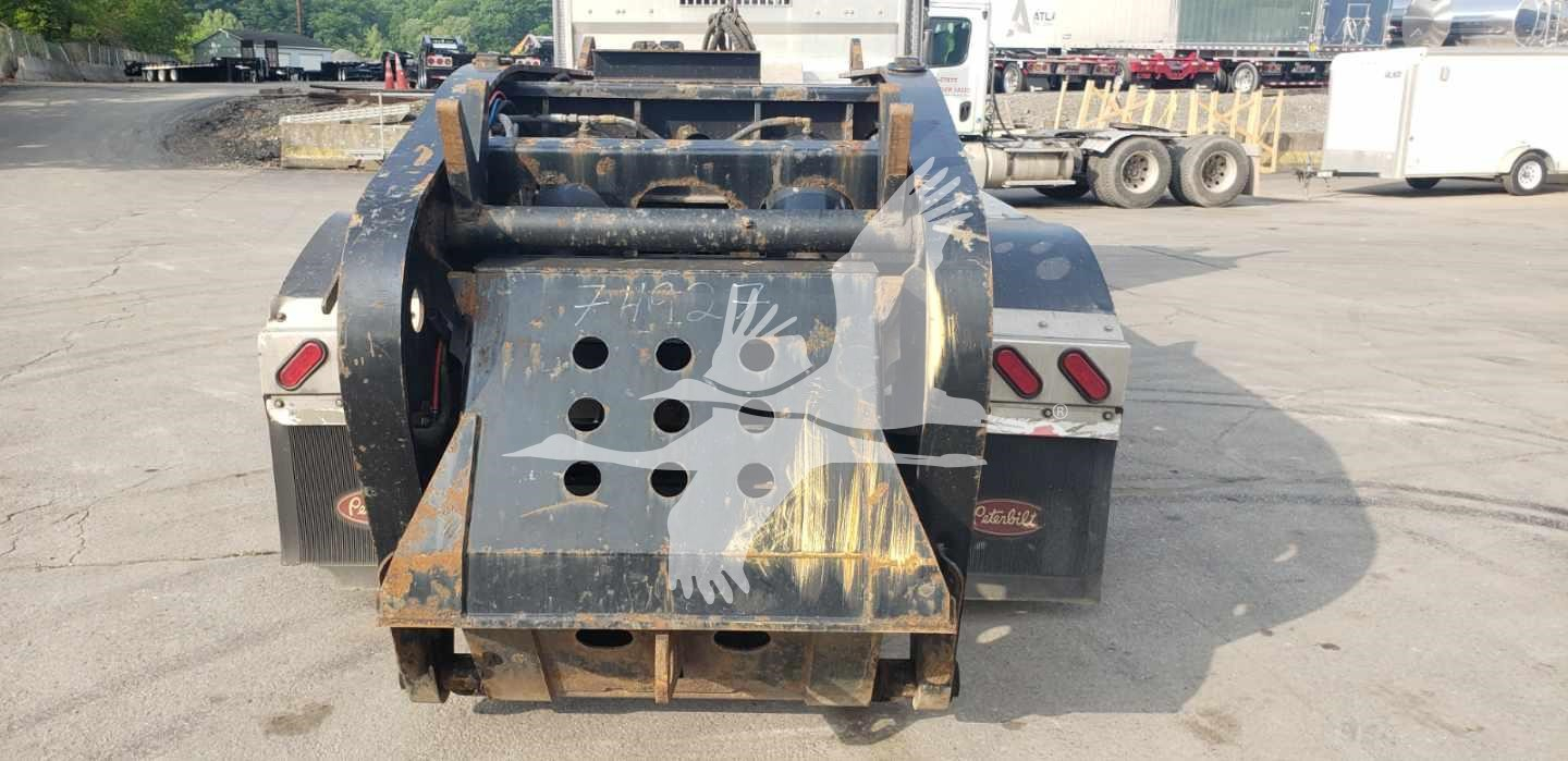 Rear view of a Fontaine 55H-DSR lowboy trailer showing mud/dust on black steel, ramp/neck area with multiple circular cutouts and tail lights.
