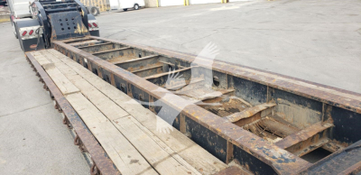 Trailer frame with long flatbed/lowboy, metal beams and wooden decking, rusty in-service condition, Fontaine brand 55H-DSR trailer visible.