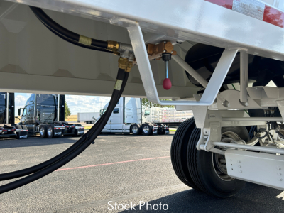 Trailer undercarriage showing hydraulic hoses and wheel assembly on a white dump trailer, with stock photo label.
