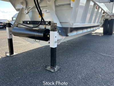 Trailer landing leg and undercarriage of a dump trailer with hydraulic cylinder and support jack visible.