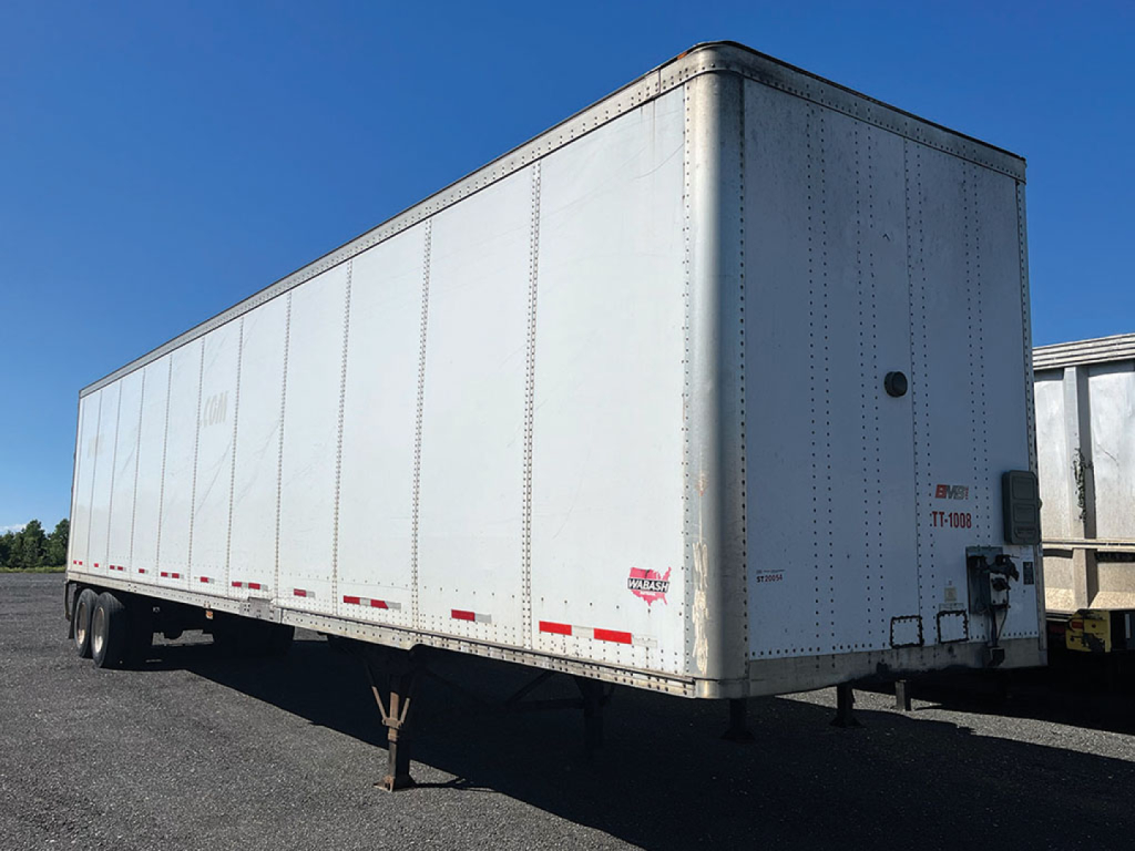 Rectangular white Wabash DuraPlate trailer with raised rivets, rear doors not visible, side view showing smooth aluminum panels and wheel area, no visible text legible