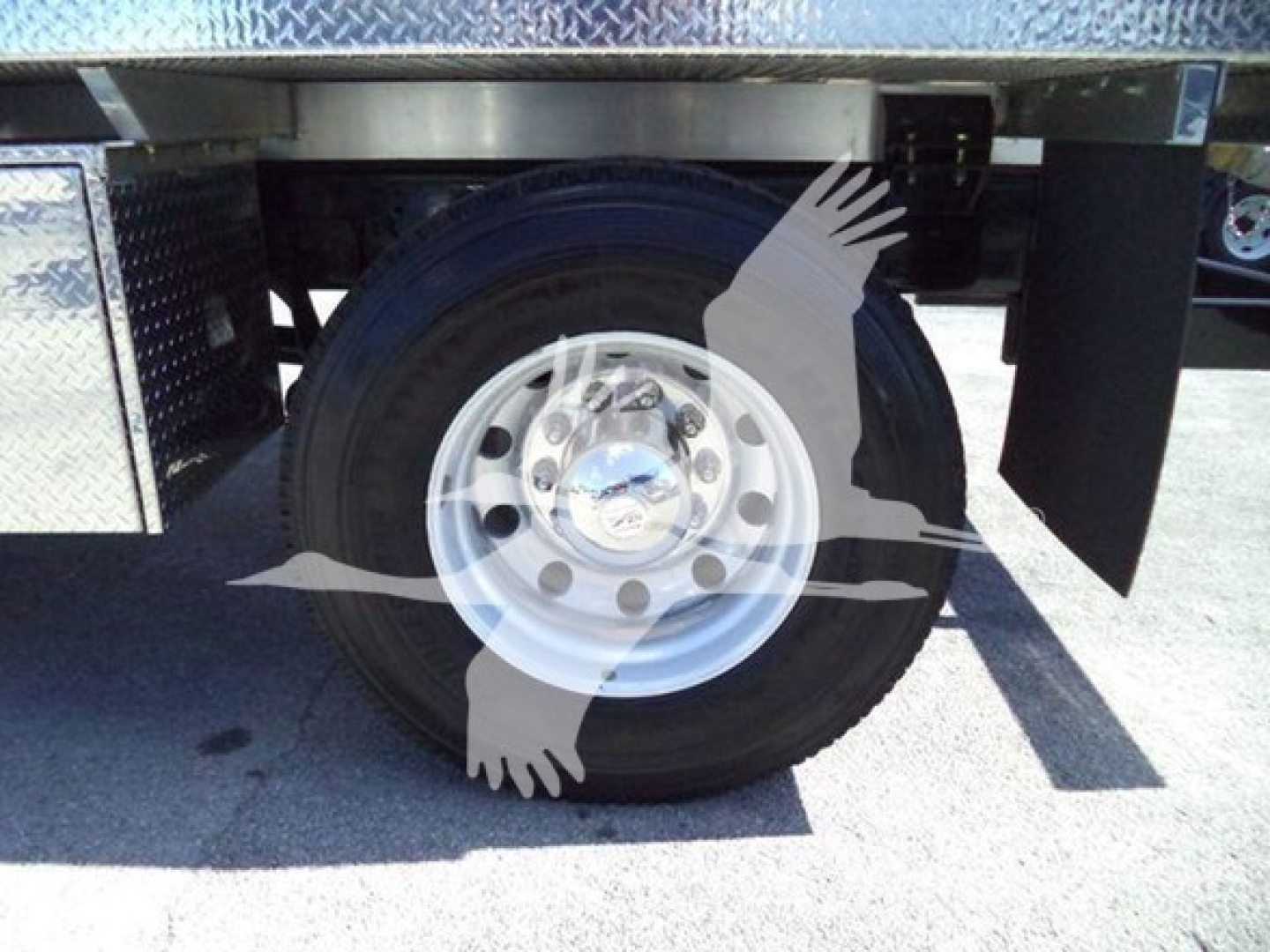 Truck wheel and tire under flatbed with diamond plate; viewers see the rear dual wheel on a 2021 International MV septic truck.