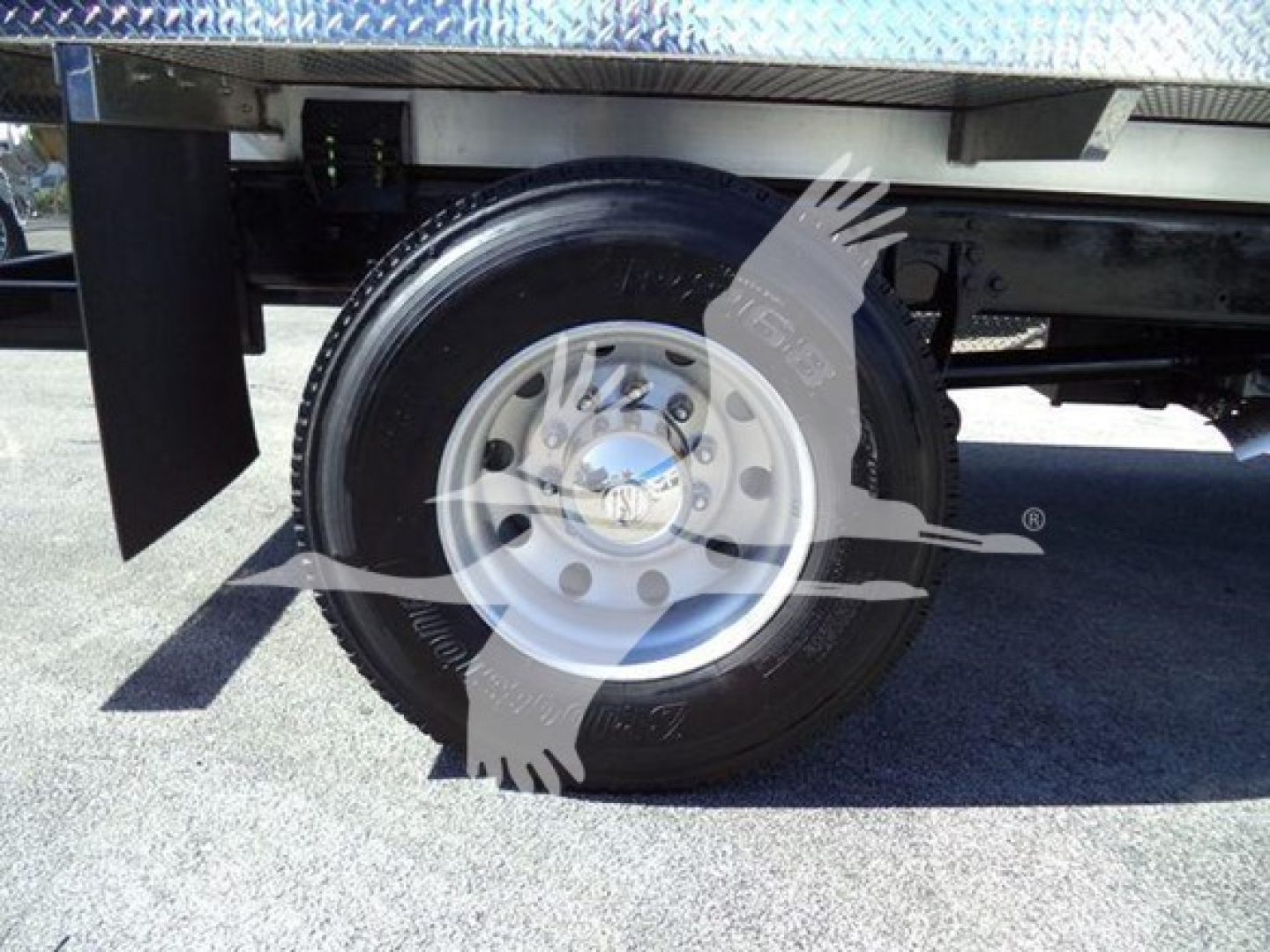 Wheel and tire of a 2021 International MV sewer rodder truck with steel rim and black tire; undercarriage view showing suspension components and wheel well.