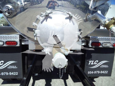 Truck rear showing circular tanker plug with chain and fittings, reflective surface, bumper lights, and mud flaps