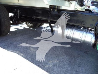 Partial undercarriage of a truck showing a cylindrical exhaust/drive component and chassis around; no legible labels visible.