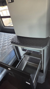 2017 Kenworth T680 sleeper cab interior showing a storage drawers and a small step, with a quilted bed surface and overhead cabinet.
